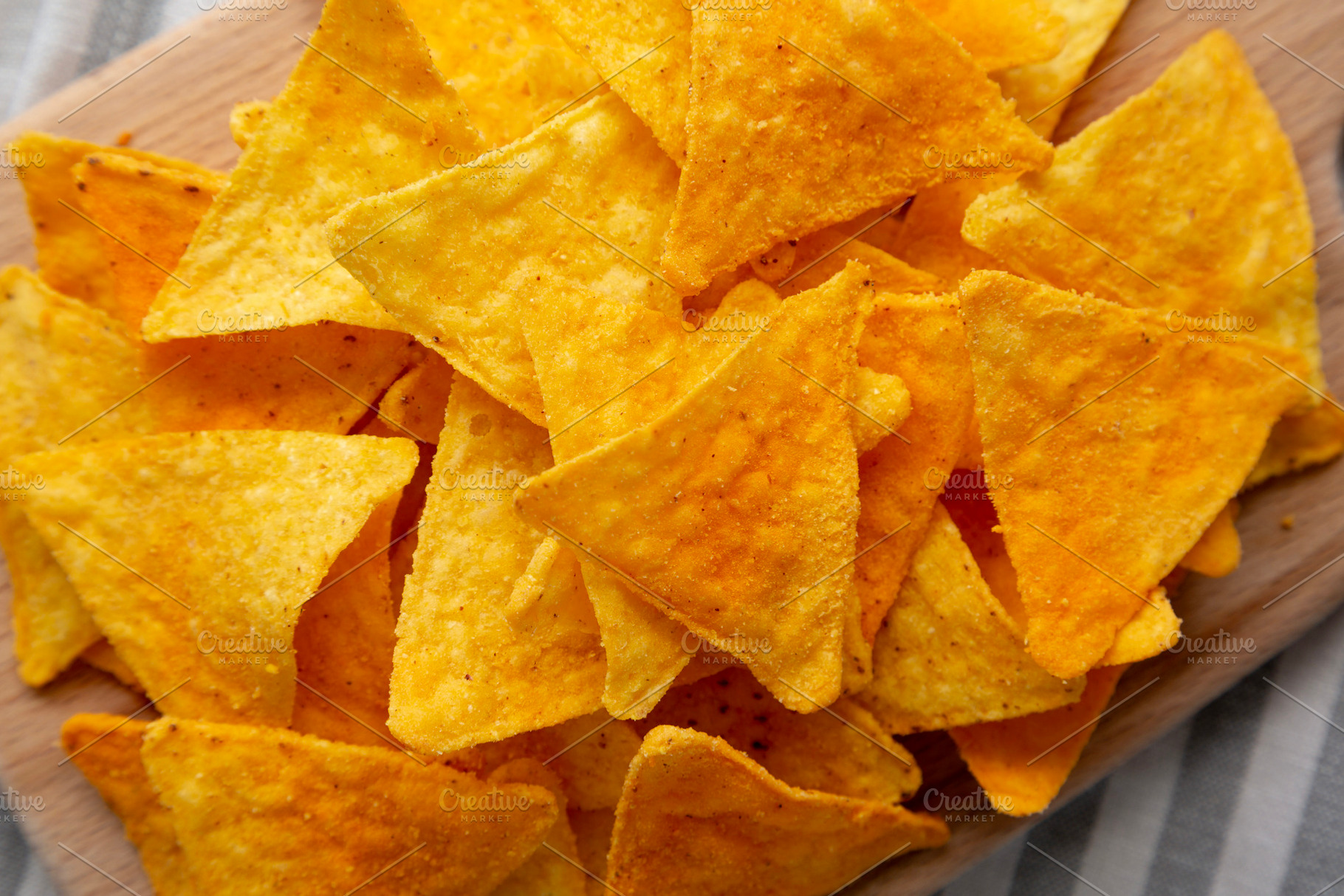 Mexican Nacho Cheese Tortilla Chips on a Board, top view. Close-, a Food & Drink Photo by LiudmylaChuhunova