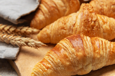 Freshly baked croissants resting on wooden cutting board with wh