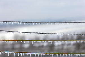 Rows of icicles hanging from metal wires outdoors on a cold wint, an Industrial Photo by Ales Munt