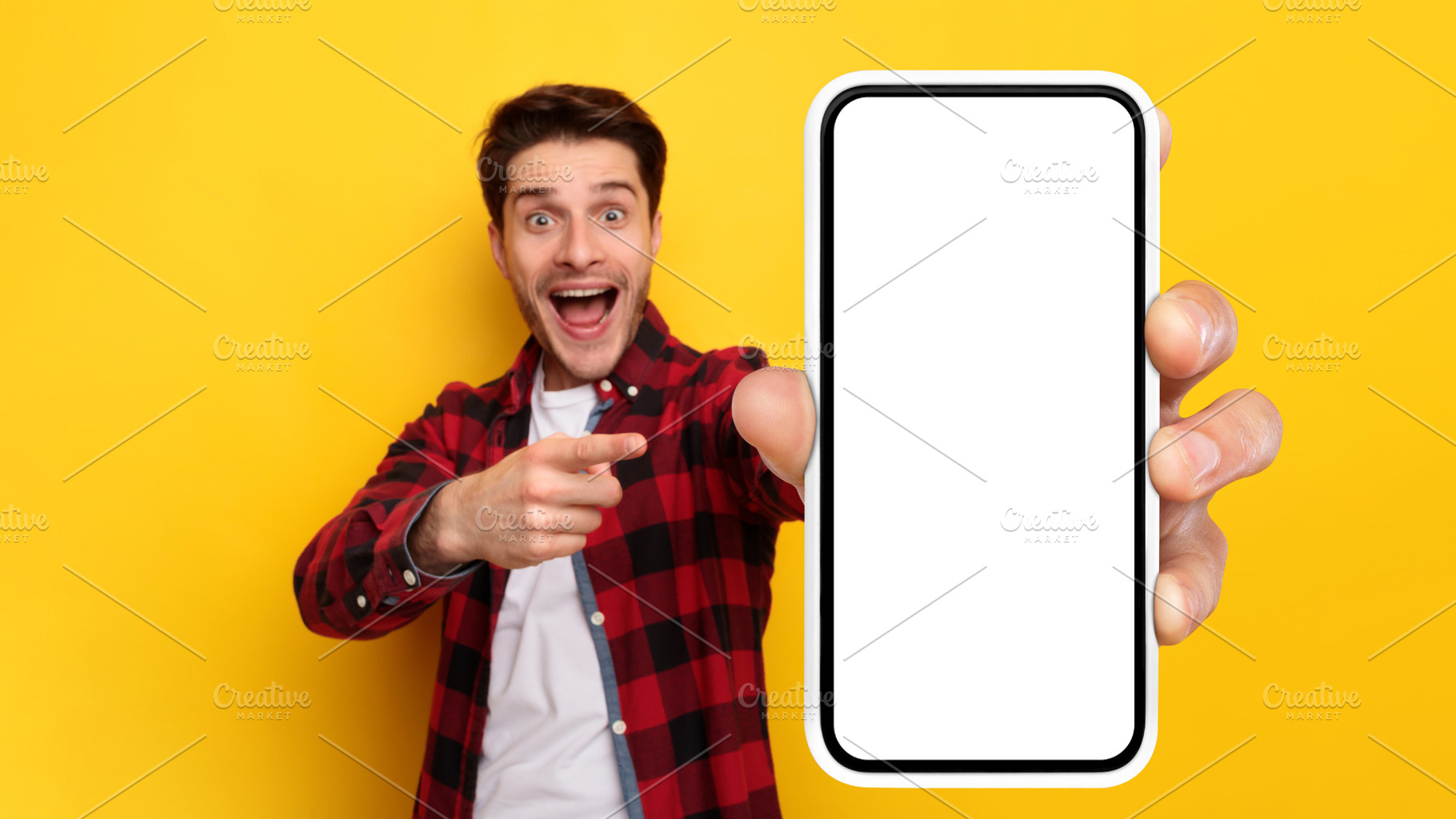 Shocked guy pointing at white empty smart phone screen, a Photo by Prostock-Studio