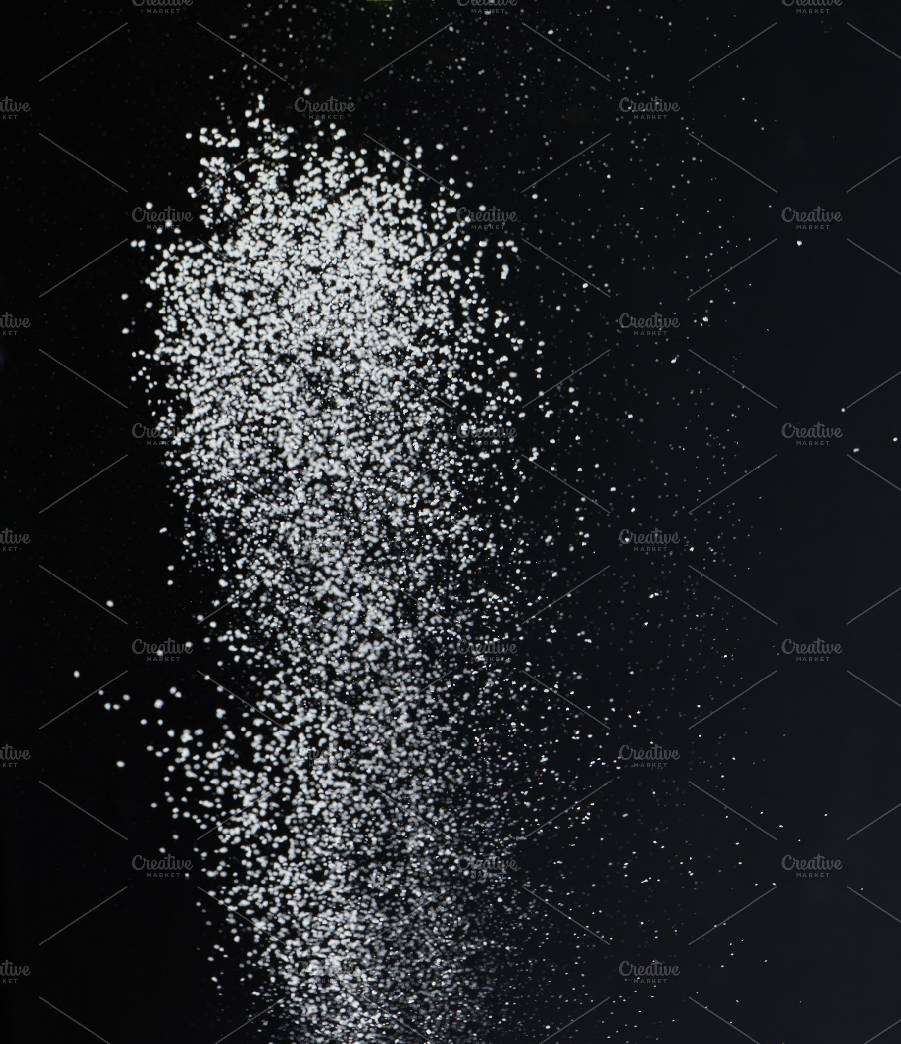 Close-up of white granular particles sugar, falling against a bl, a Food & Drink Photo by ndanko