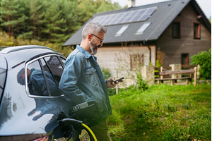 Man charging electric car in front, a Transportation Photo by HalfPoint