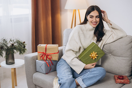 Beautiful happy woman unwrapping New Year or Christmas presents