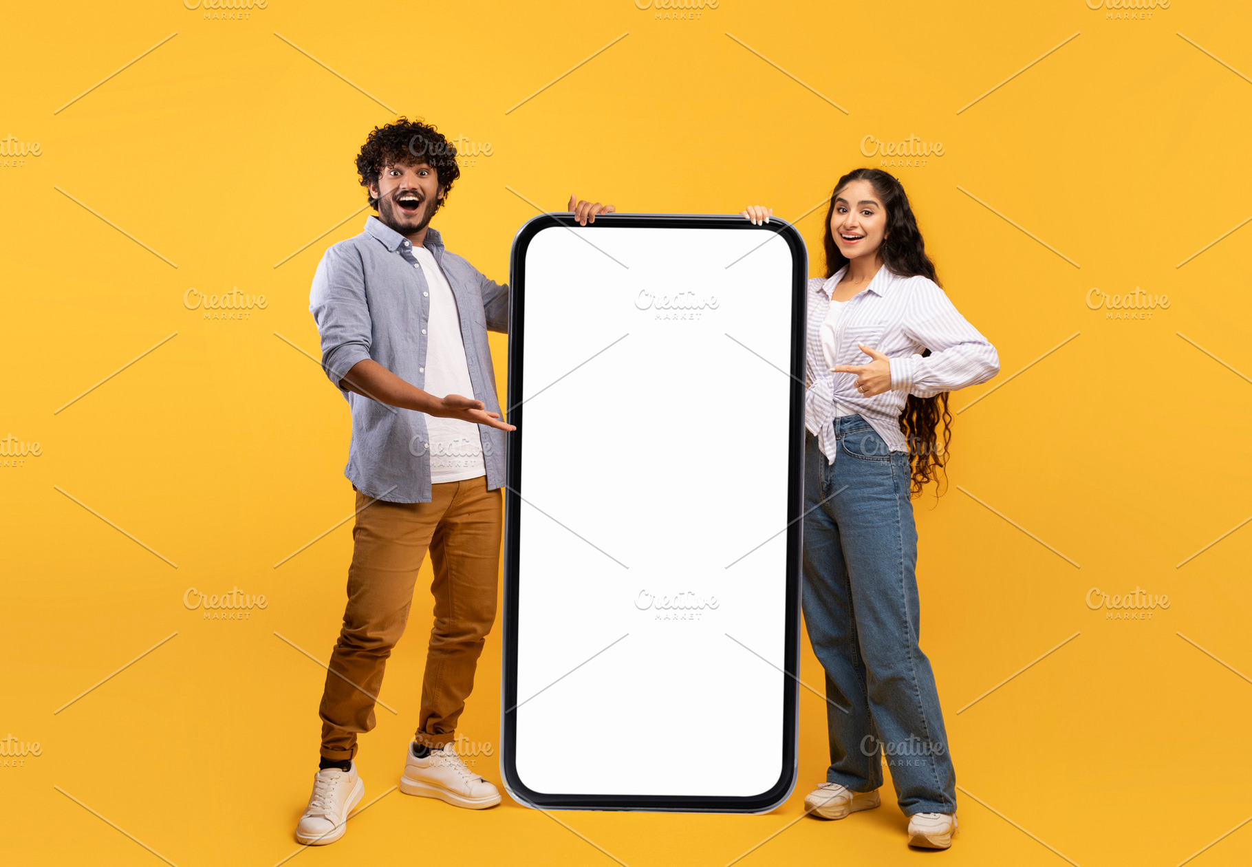 Cool mobile offer. Happy indian couple pointing at big cellphone with white scr, a Person Photo by Prostock-Studio