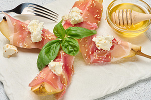 Pear slice wrapped in prosciutto with cheese and sesame seeds on, a Food & Drink Photo by ndanko