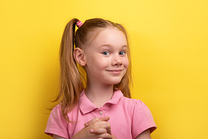 Playful young girl in pink shirt clasping hands and smiling conf, a Person Photo by Ales Munt