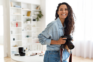 Cheerful Arabic Photographer Woman Holding Photo Camera Indoors, a Photo by Prostock-Studio