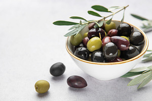 Fresh olives with olive branch in white bowl on marble table, a Food & Drink Photo by Olena Rudo