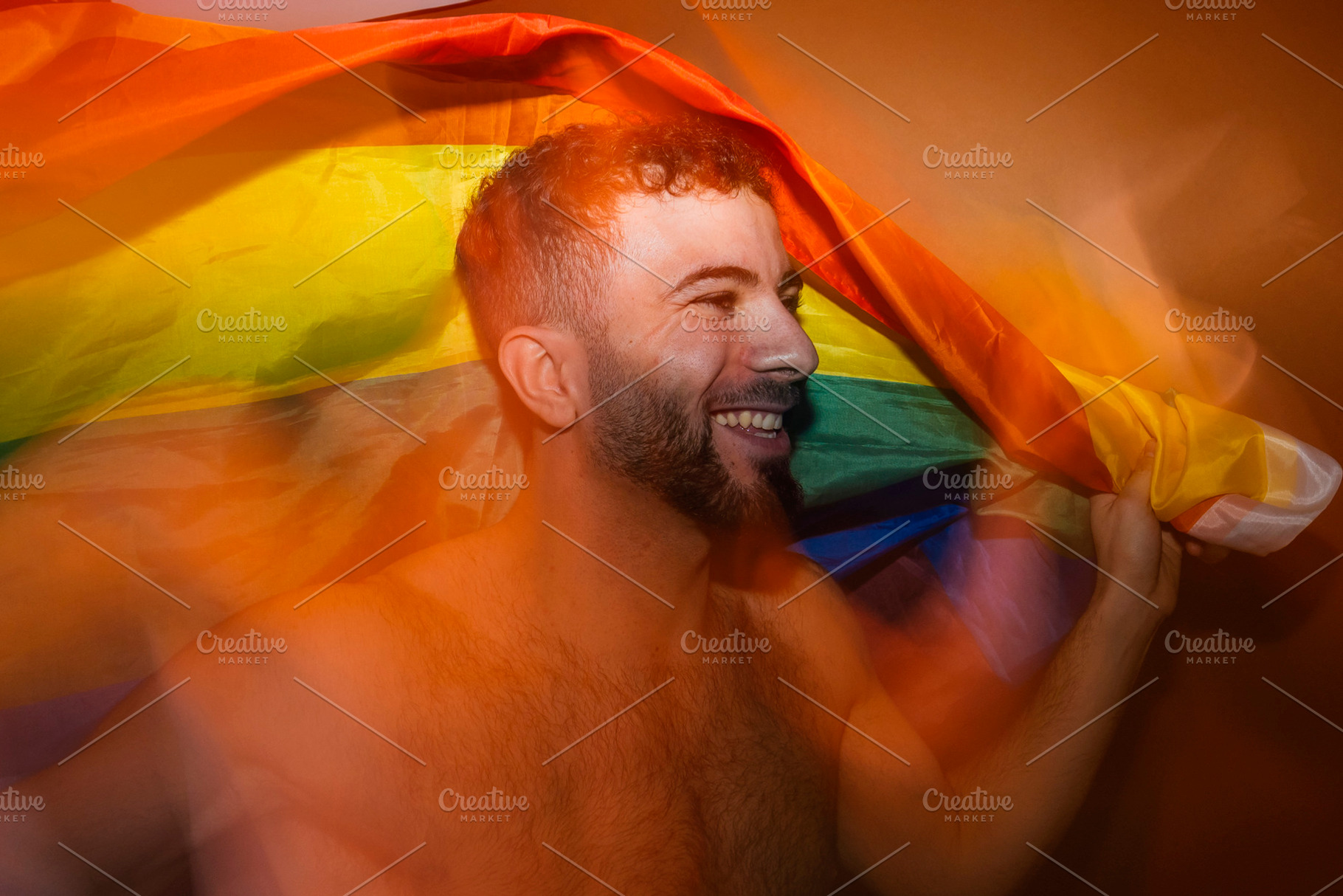 Gay man celebrating pride with rainbow flag, a Photo by karrastock