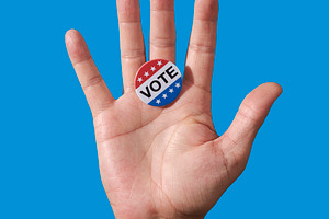 man displaying vote badge on open palm, a Photo by Nito