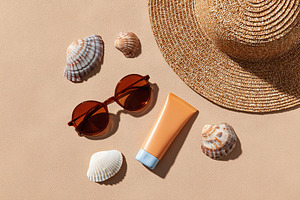 Summer beach essentials arranged on warm sand with seashells and accessories, a Beauty & Fashion Photo by AlyaAnd