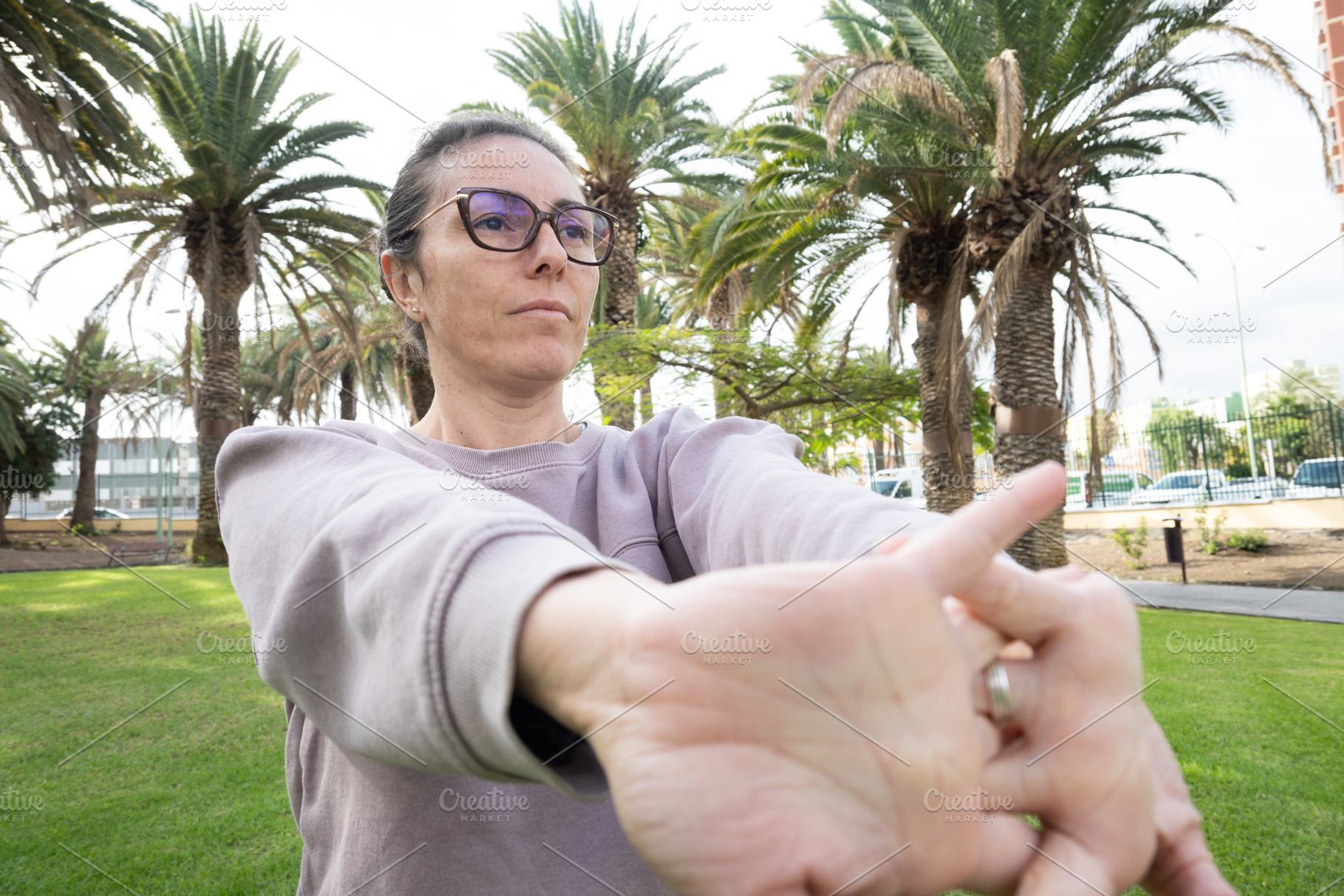 Woman stretching arms outdoors in a park with palm trees, a Person Photo by etorres69