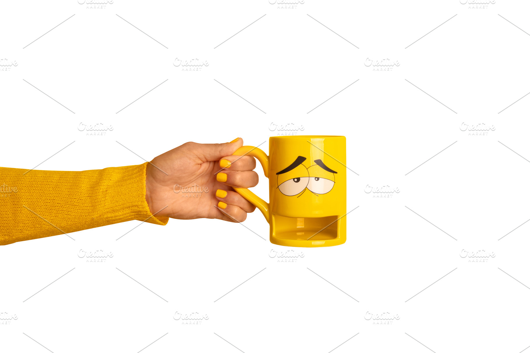 Hand holding a yellow mug with a sad face design, matching yello, a Food & Drink Photo by Ales Munt