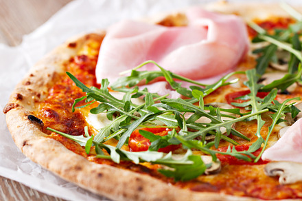 Hot italian pizza with prosciutto and arugula on a table., a Food & Drink Photo by FoodStock
