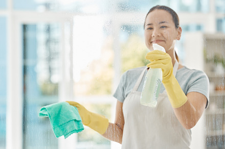 Housekeeping, products and happy woman cleaning the windows with detergent, cloth and gloves. Maid, cleaner or domestic worker washing the dust and bacteria off the glass in an apartment building., a Photo by Peopleimages.com