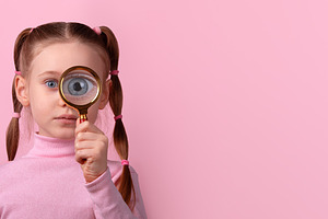 Young girl with pigtails holding magnifying glass to her eye, st, a Person Photo by Ales Munt