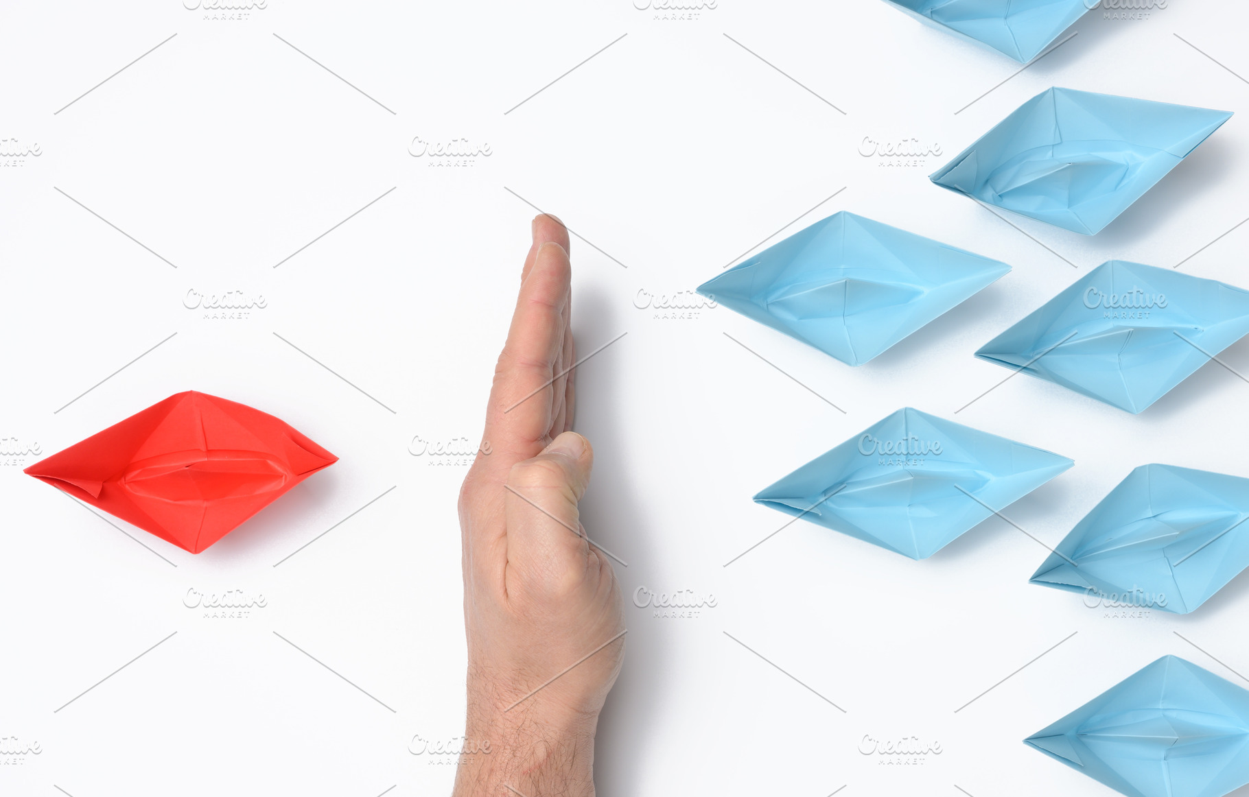 A hand stops a red paper boat while blue ones float past. The co, a Business Photo by ndanko
