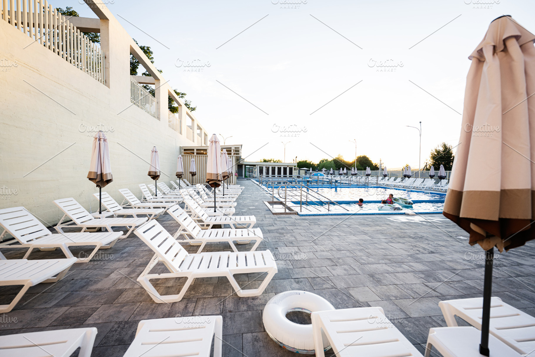 Outdoor swimming pool with white loungers and umbrellas during daytime, a Photo by AS photostudio