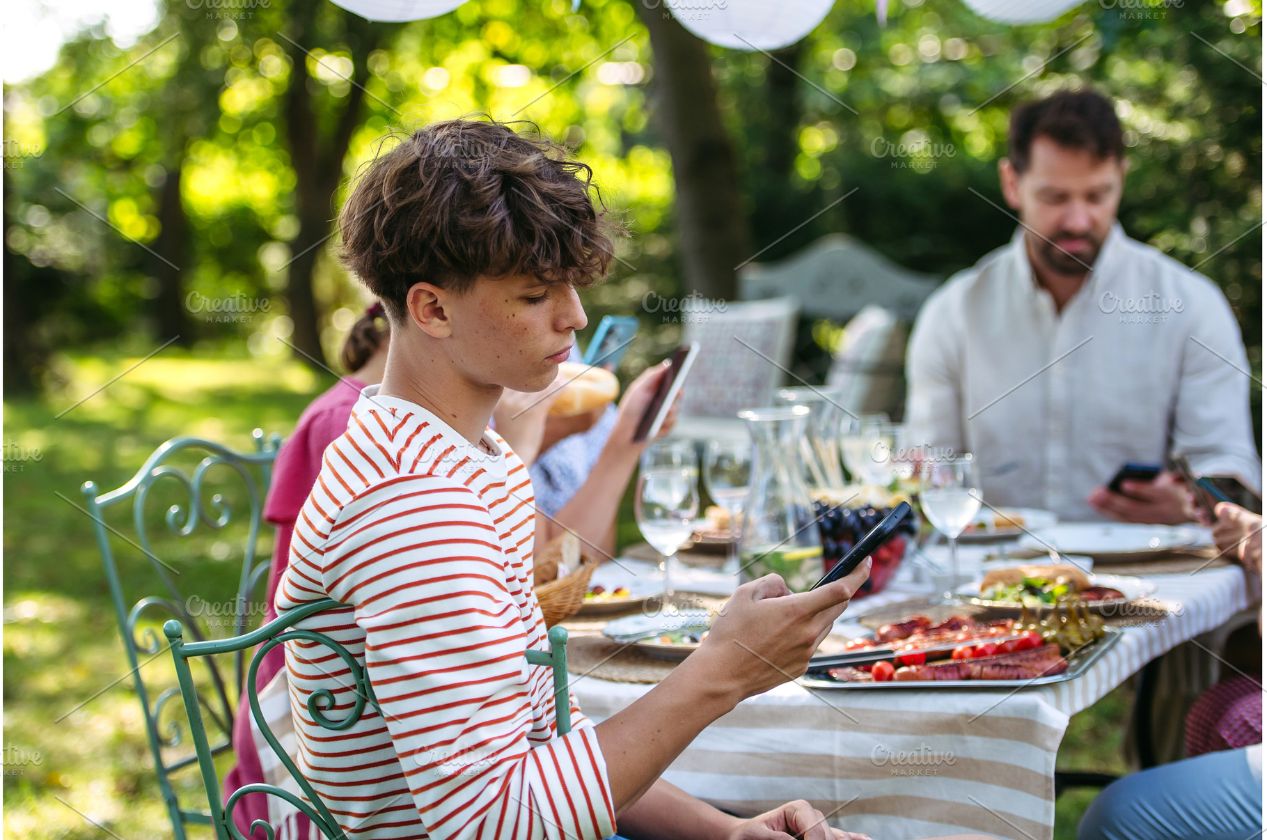 Boy looking at phone during family, a Person Photo by HalfPoint