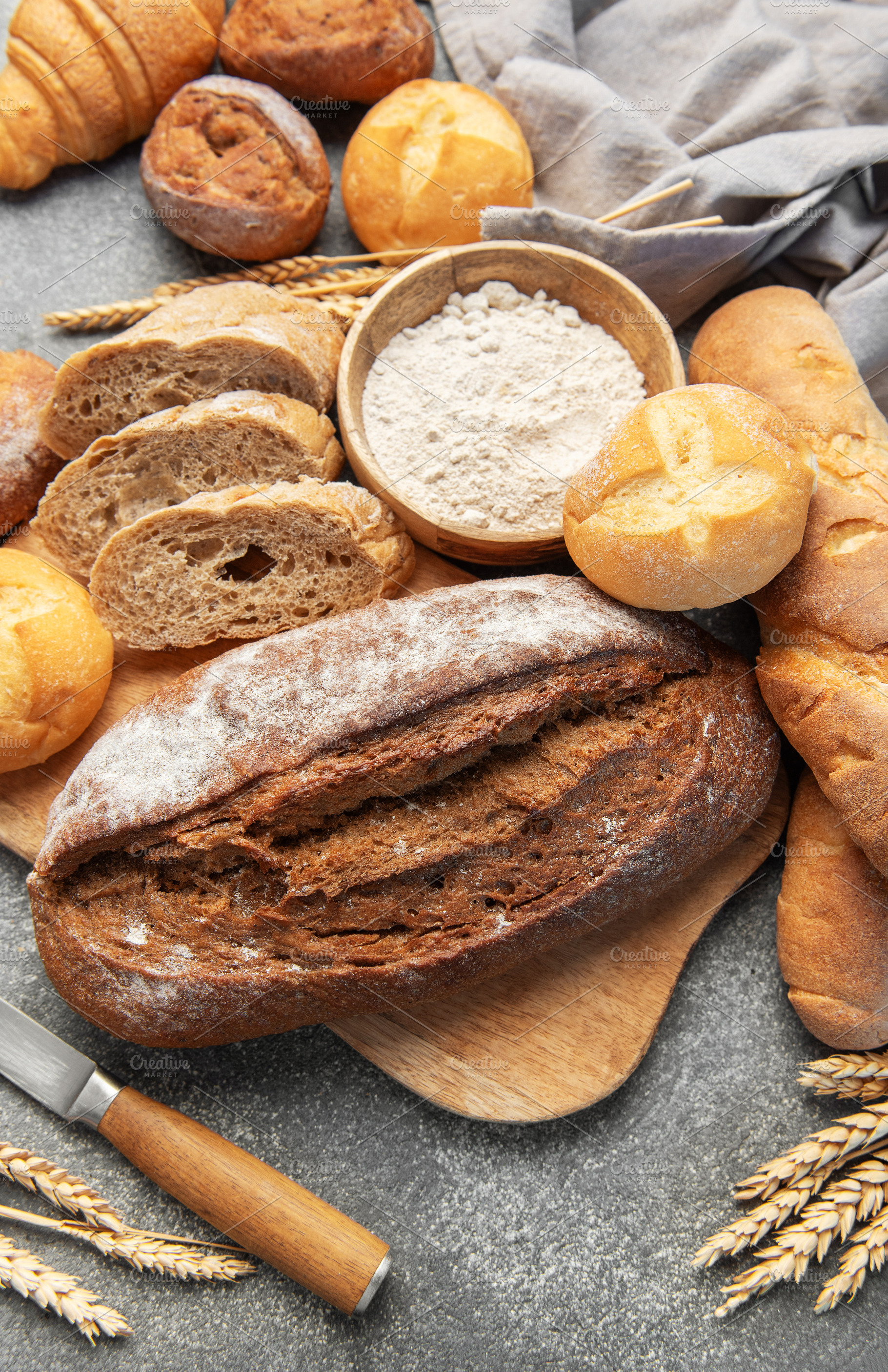 Fresh baked bread, baguettes, buns, and flour on concrete, a Food & Drink Photo by Olena Rudo