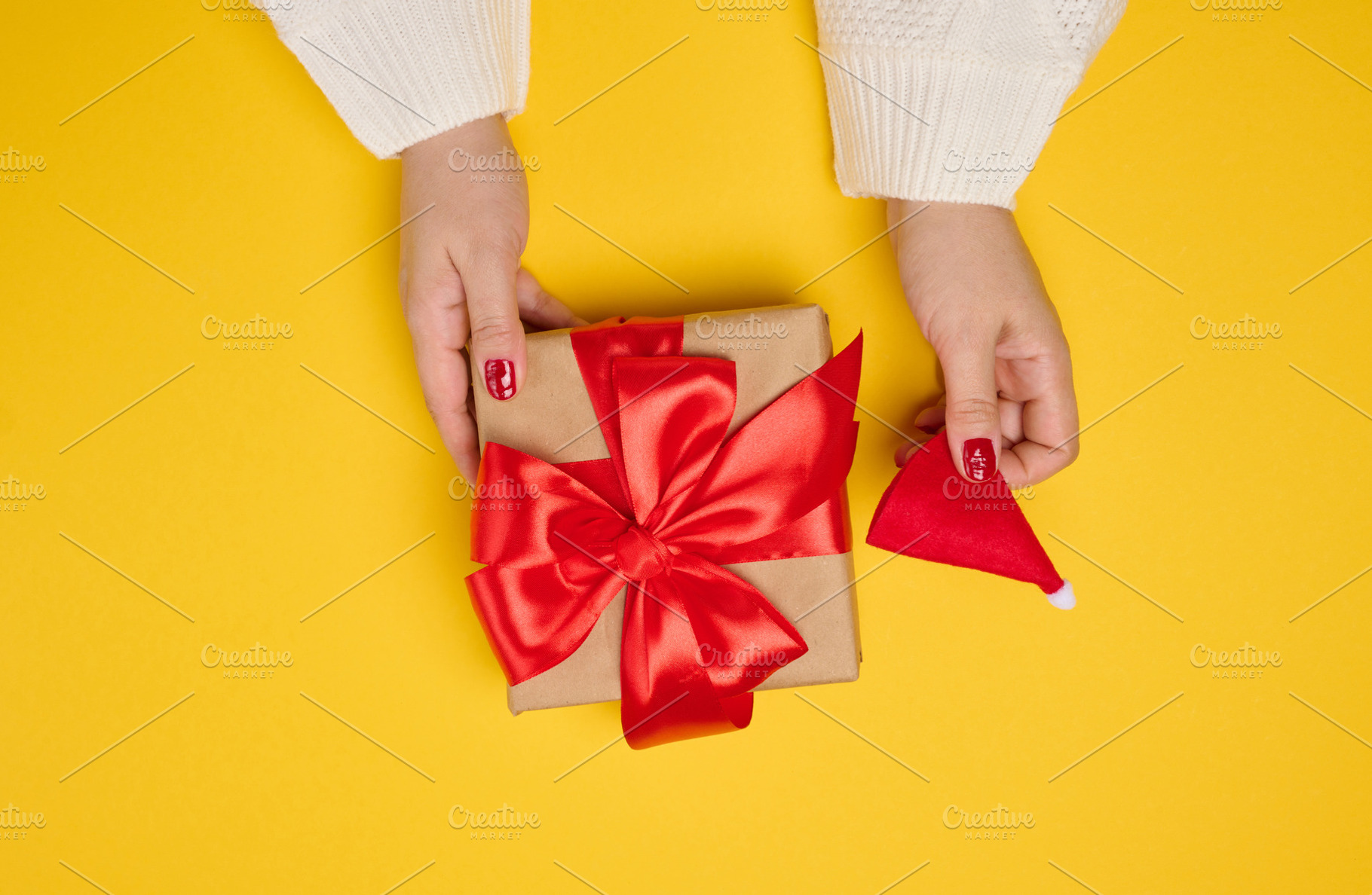 Two female hands in a white knitted sweater hold a square gift b, a Holiday Photo by ndanko