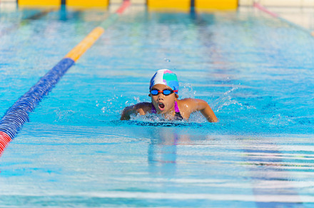Swimmer child swims butterfly swimming style in a race swimming
