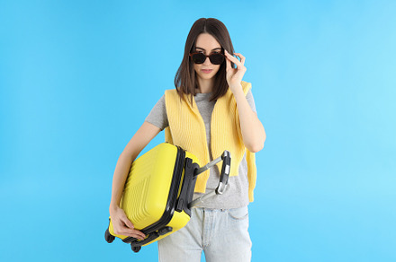 Attractive woman with travel bag on blue background, a Person Photo by AtlasStudio PRO