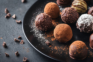 Mixed truffles on black plate, a Photo by Beautiful things