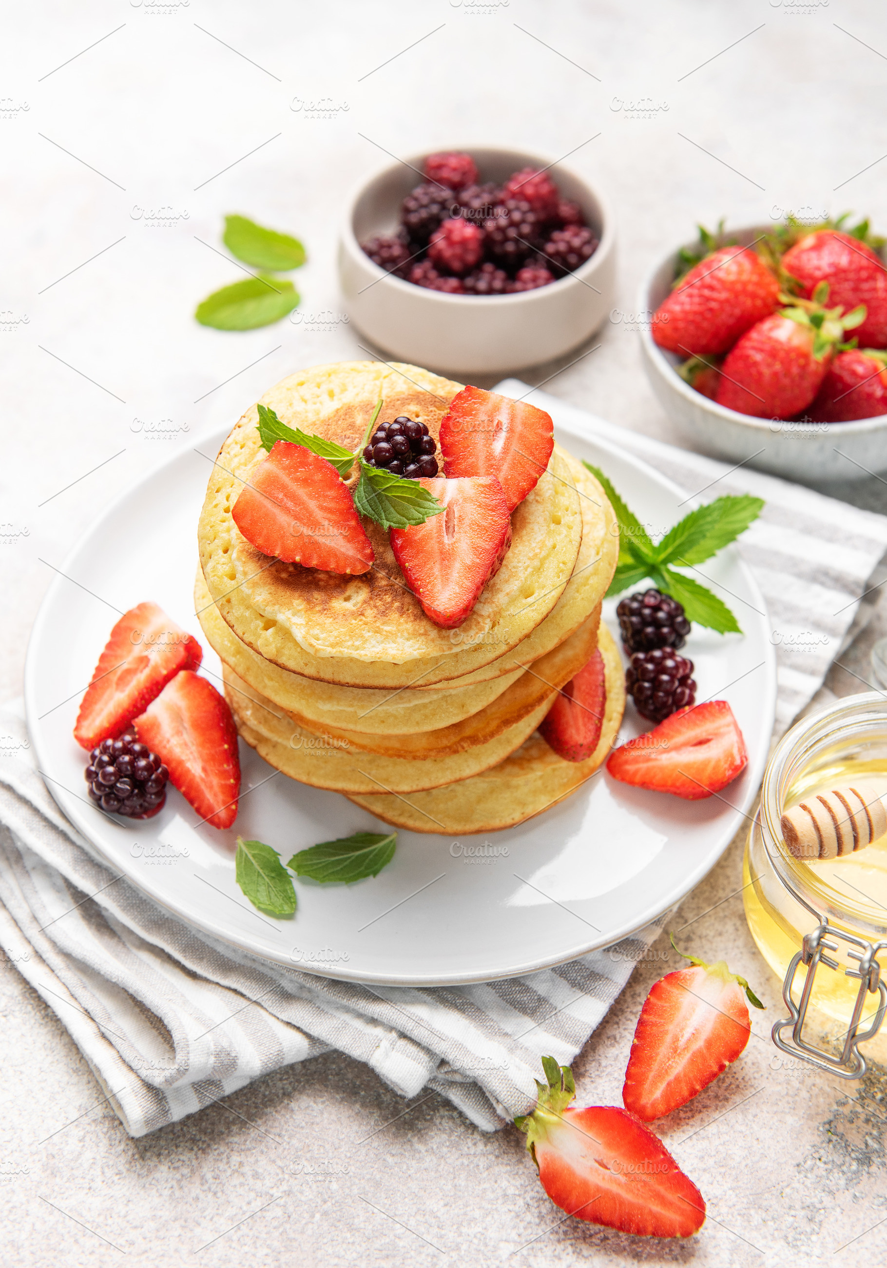 Stack of pancakes with fresh berries and honey, a Food & Drink Photo by Olena Rudo