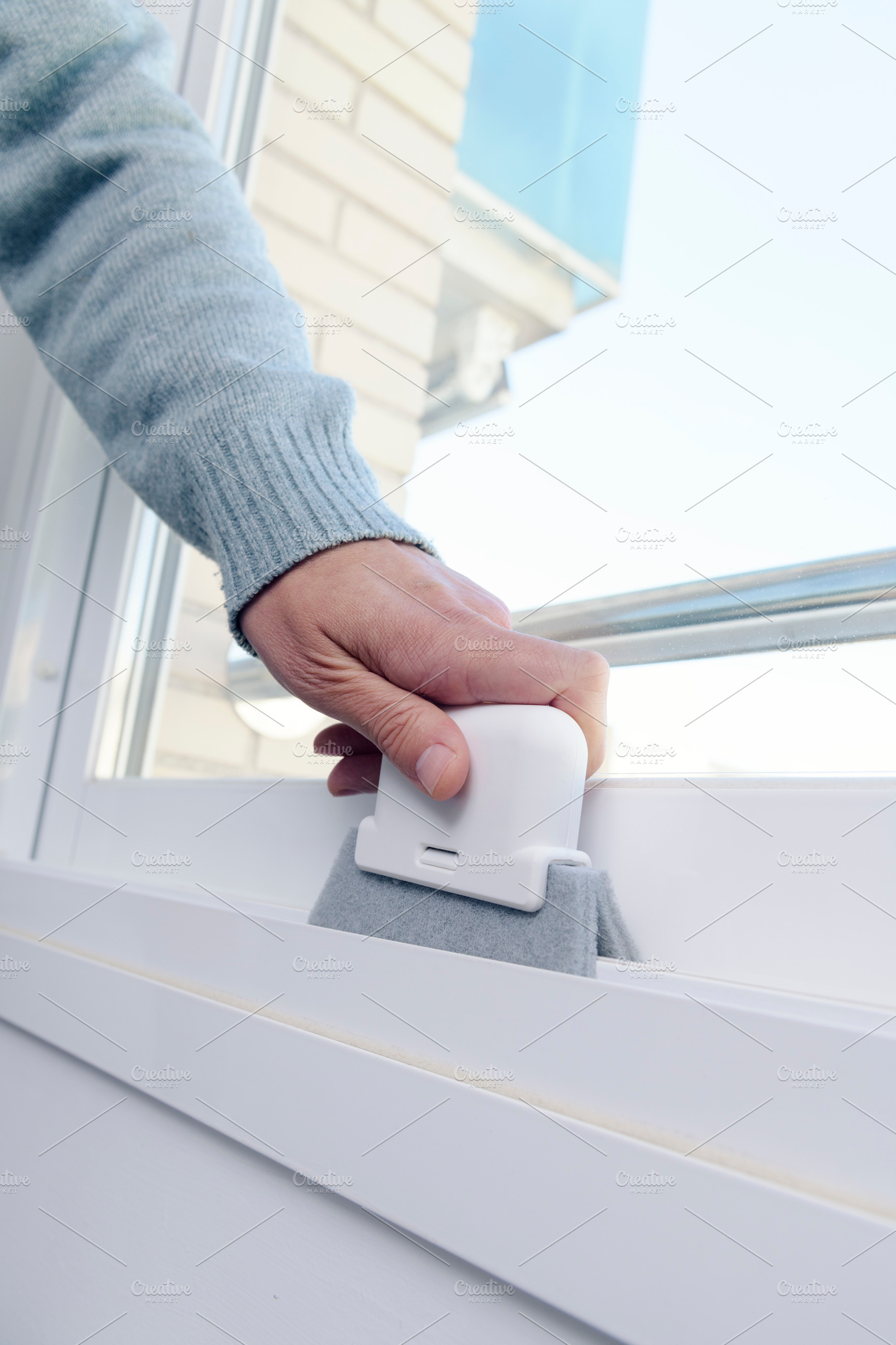 a man cleans the grooves of a sliding window frame, a Photo by Nito
