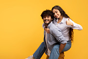 Great offer. Excited indian man piggybacking girlfriend and woman showing thumb, a Photo by Prostock-Studio (Thumbnail 2 of 3)