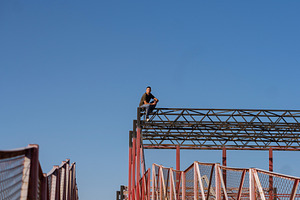 Freerunner rests atop high structure, a Person Photo by Elena Vagengeim