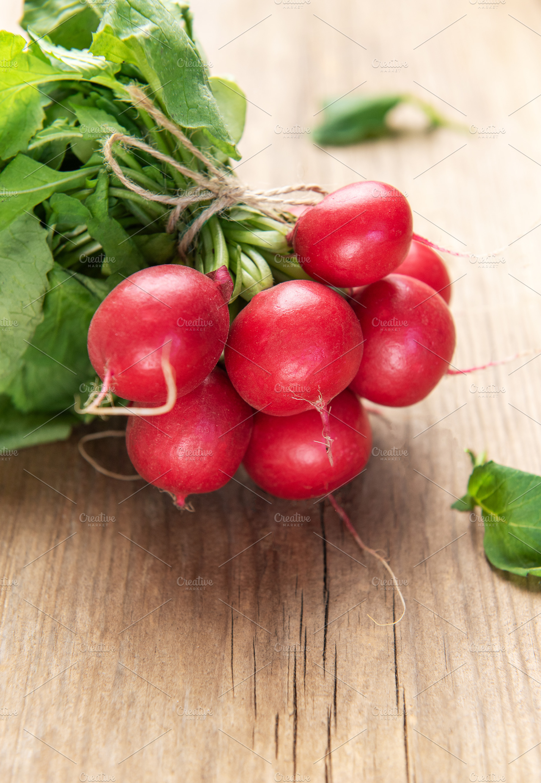 Fresh whole radishes with green tops on wooden surface, a Food & Drink Photo by Olena Rudo