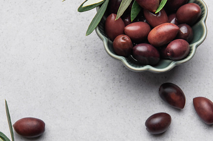 Kalamata olives with olive branch in green bowl on marble backgr, a Food & Drink Photo by Olena Rudo