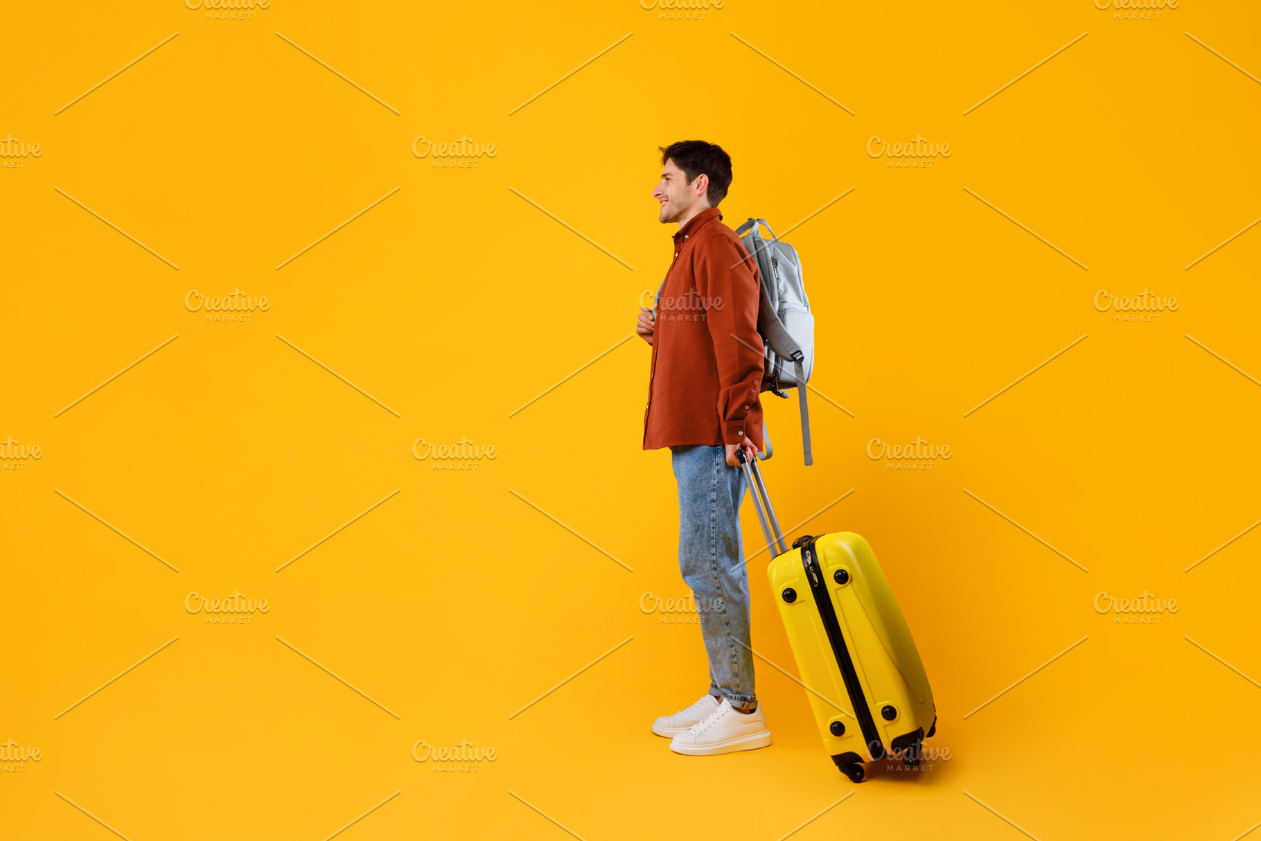 Traveler Guy With Travel Suitcase And Backpack On Yellow Background, a Photo by Prostock-Studio