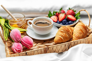 Romantic breakfast in bed with coffee, croissants, berries, hone, a Food & Drink Photo by Olena Rudo