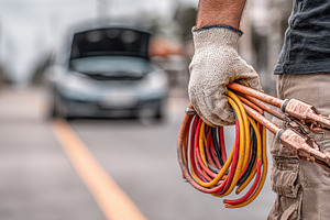 Mechanic holding jumper cables roads, a Photo by Pixeness Studio