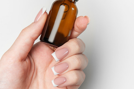 Woman hand holding cosmetic dropper bottle on white background
