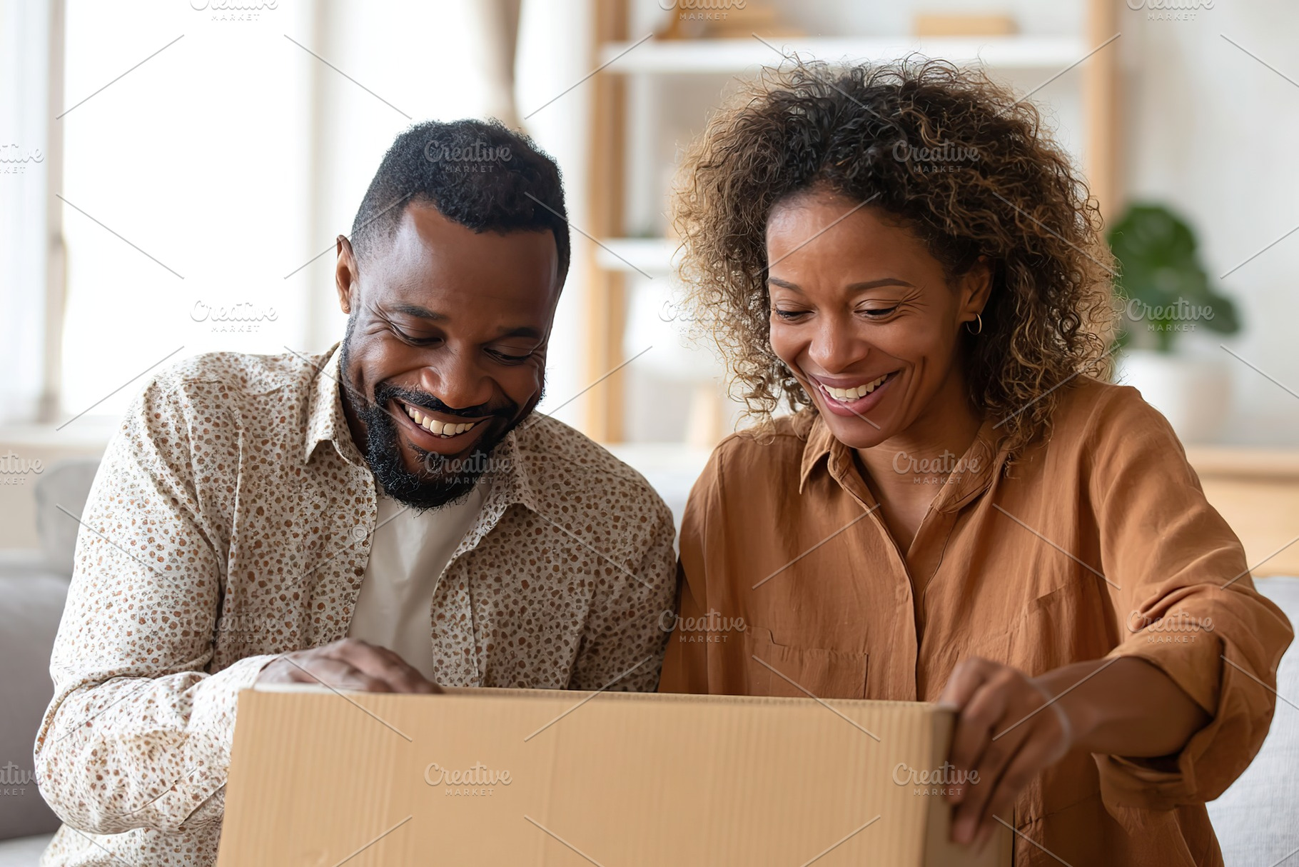 Joyful couple opening a surprise package together in their cozy living room, a Photo by AlyaAnd