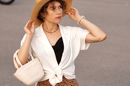 Woman adjusts straw hat posing