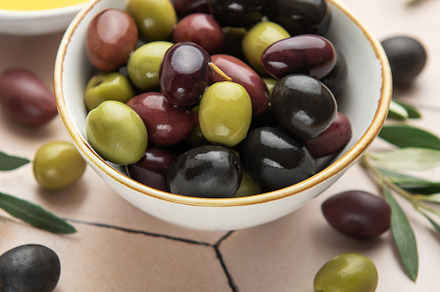 Bowl of assorted olives with olive oil and olive branches on til, a Food & Drink Photo by Olena Rudo