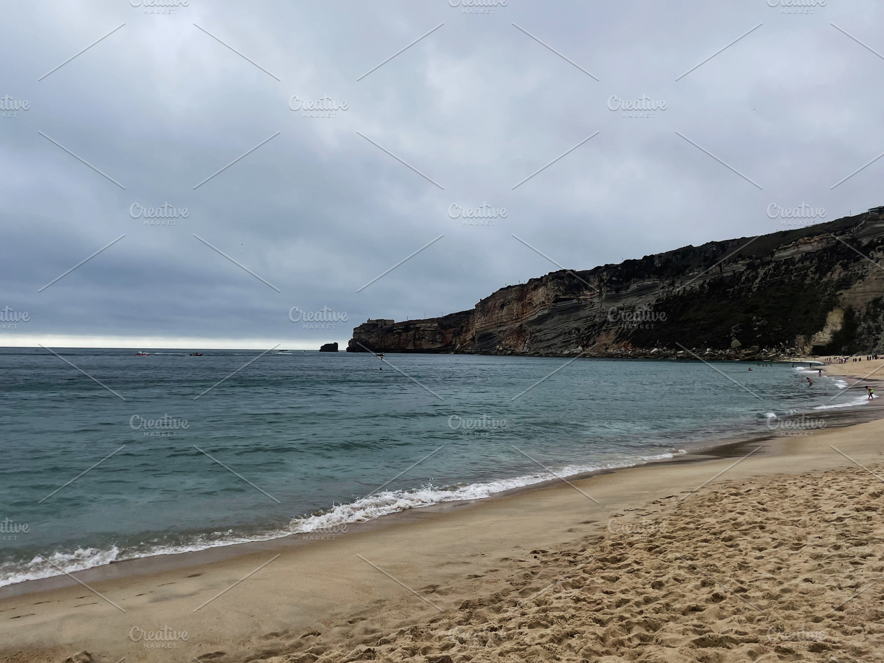 Serene beach with cliffs and cloudy sky in Nazare, Portugal, a Photo by AS photostudio