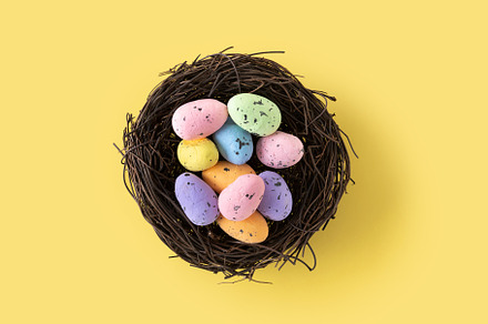 Colorful Easter eggs inside a nest on yellow background. Copy sp, a Holiday Photo by etorres69