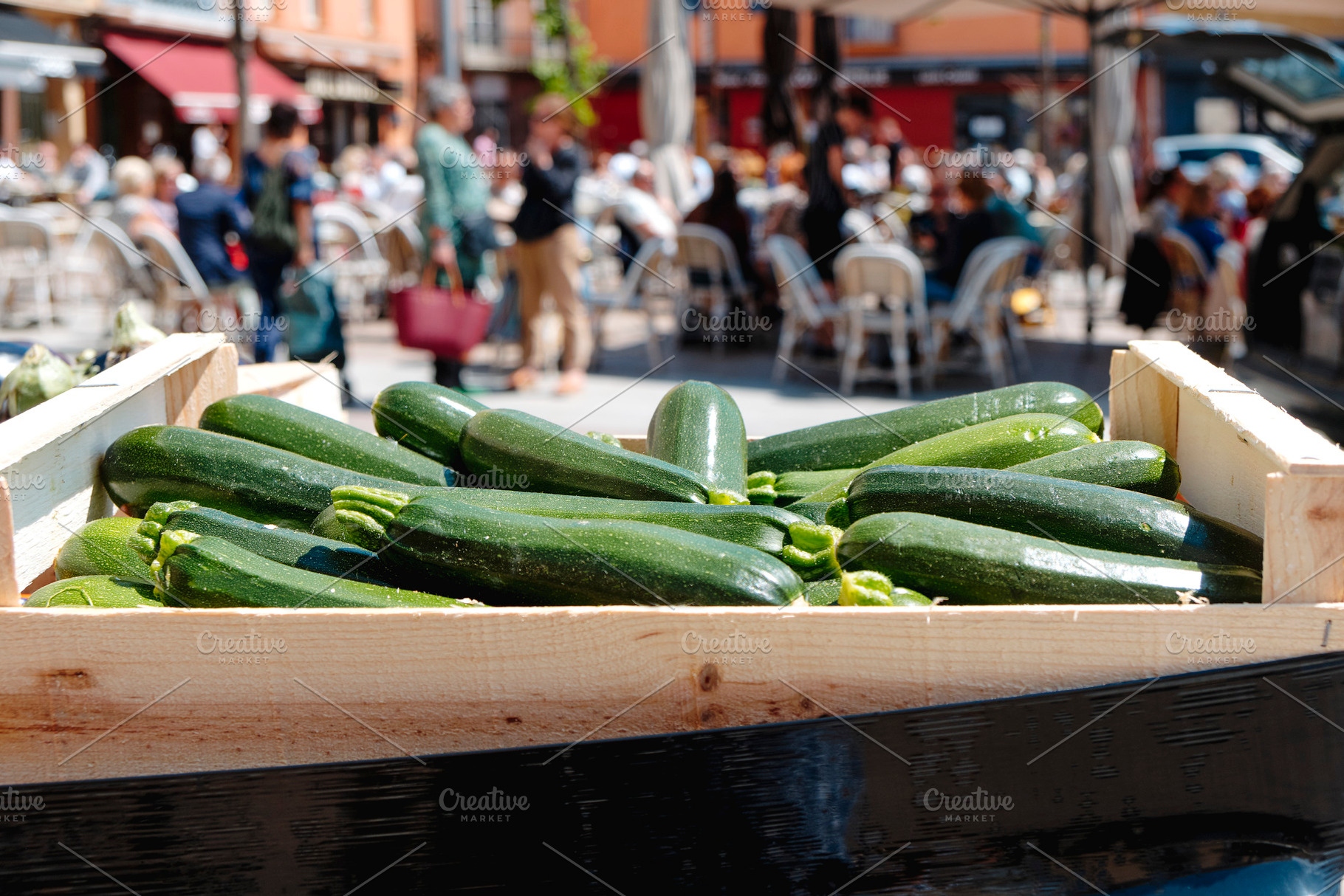 crate with zucchinis for sale at farmers market, a Photo by Nito