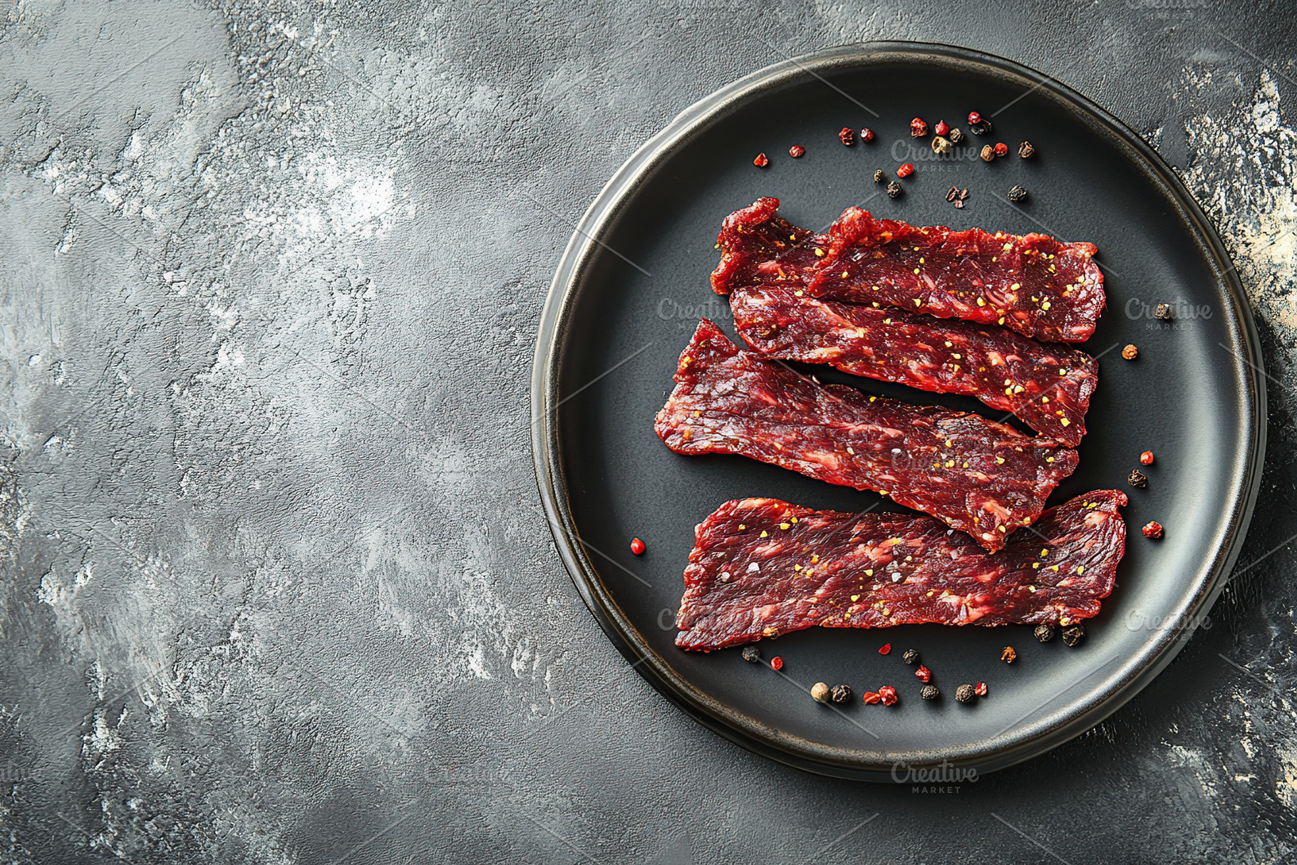 Spicy beef jerky on grey background, a Food & Drink Photo by AlyaAnd
