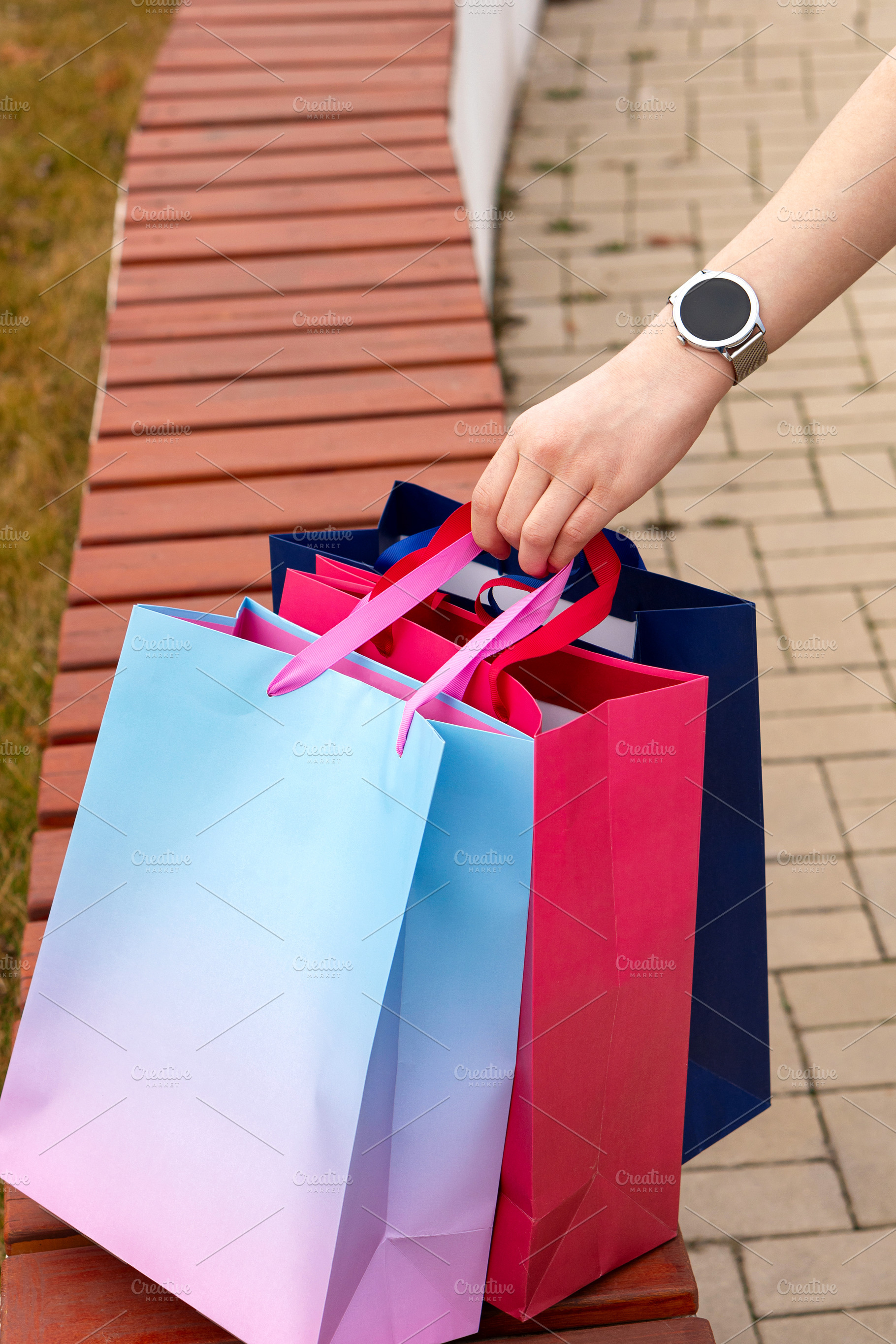 Shopper's hand grasping vibrant bags, a Background Photo by Elena Vagengeim