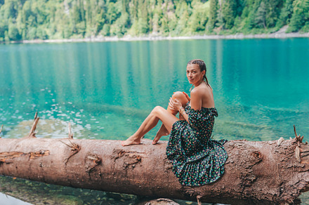 Happy romantic woman sitting by lake splashing water at perfect blue Lake Ritsa, a Person Photo by travnikovstudio