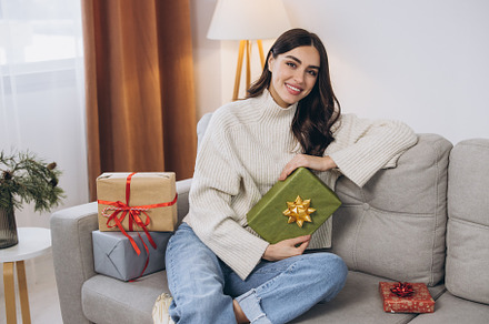 Beautiful happy woman unwrapping New Year or Christmas presents