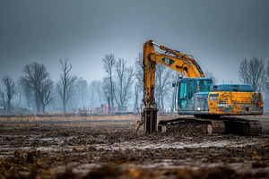 Excavator in muddy field under gloom, a Photo by Pixeness Studio