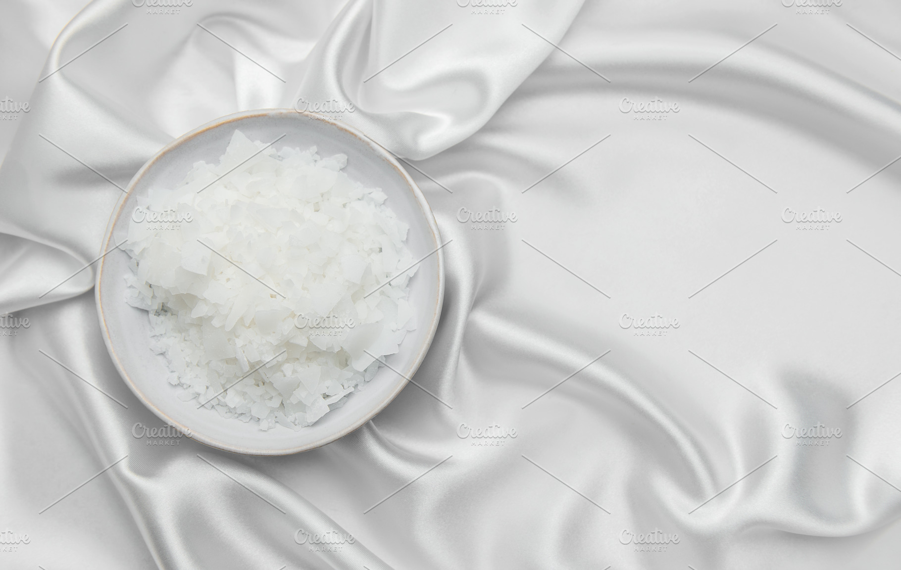 Magnesium flakes in a bowl resting on elegant white silk fabric, a Health & Medical Photo by Olena Rudo